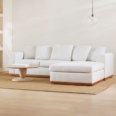 a white couch sitting on top of a hard wood floor next to a coffee table