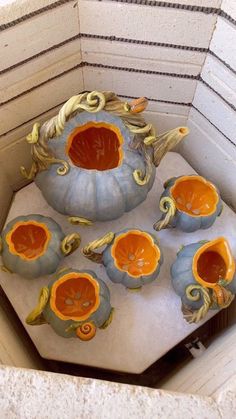 an arrangement of pumpkins and gourds are on display in a room with white walls