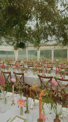 tables set up with flowers and candles for an outdoor wedding reception in a tented area