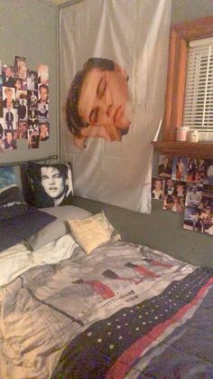 an unmade bed in a bedroom with pictures on the wall and clothes hanging up