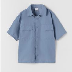 Zara Technical Nylon Shirt Blue - Size: Available In 13-14 Years In Kid's Size ( Equivalent To Size Xs In Women's) - Color: Blue - Materials: 71% Nylon, 29% Cotton. - Technical Nylon Shirt With Lapel Collar And Short Sleeves. - Front Snap Button Closure. - Front Flap Pockets. Light Blue Summer Shirt With Pockets, Light Blue Shirt With Pockets For Summer, Casual Blue Shirt With Pockets, Blue Relaxed Fit Short Sleeve Shirt For Spring, Blue Short Sleeve Tops With Pockets, Casual Blue Tops With Pockets, Light Blue Tops With Pockets For Spring, Blue Button-up Zara Tops, Zara Short Sleeve Tops With Pockets