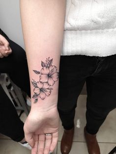 a woman's arm with a flower tattoo on the left side of her hand