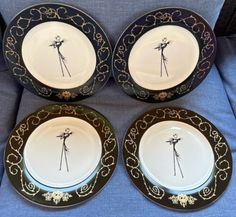 four black and gold dinner plates with palm trees on the rims, set on a blue couch