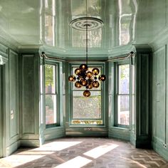 an empty room with green walls and large windows in the center is lit by sunlight