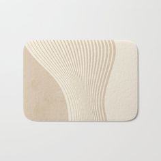 a bath mat with an abstract design in beige and white on the front, featuring wavy lines