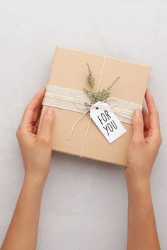 two hands holding a gift box with a tag that says for you