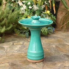 a blue bird bath sitting on top of a stone floor