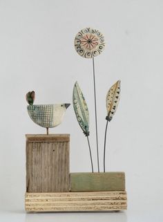 a wooden block with two birds on top of it and some flowers in the back