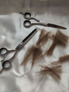 two pairs of scissors and some hair on a white sheet