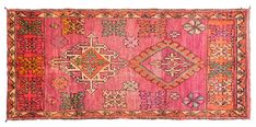 an old rug with many different colors and designs on the carpet, including pinks, orange