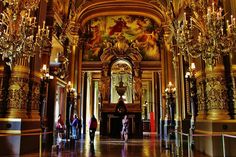 an ornate building with chandeliers and paintings on the walls