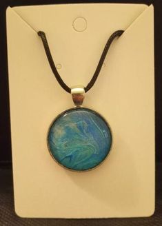 This deep blue, metallic acrylic art flow pendant has hints of silver that are subtly revealed in the light.  The art skin is set in a round silver tone color 1" bezel tray with glass cabochon dome. Black necklace cord is strong & durable waxed cotton, 24" with 2" extender chain and lobster clasp closure. Artsy Blue Metal Jewelry, Blue Hand Painted Round Pendant Necklace, Hand Painted Blue Round Pendant Necklace, Artsy Blue Round Pendant Jewelry, Artsy Round Blue Jewelry, Blue Hand Painted Round Pendant Jewelry, Artistic Blue Jewelry With Large Pendant, Artsy Blue Round Jewelry, Artsy Silver Jewelry With Large Pendant