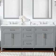 a bathroom with double sinks and mirrors on the wall next to a rug in front of it