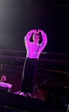 a man standing on top of a stage with his hands in the air while wearing glasses