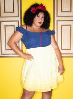 a woman in a blue top and yellow skirt posing for the camera with her hands on her hips