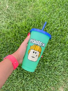 a hand holding a green cup with a cartoon character on it