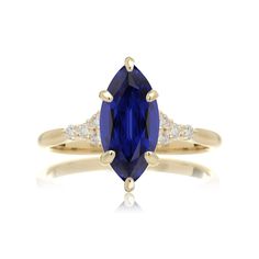 a yellow gold ring with an oval blue sapphire and two diamonds on the band, set in