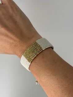 Embrace the fusion of simplicity and modern elegance with our handwoven cream and gold bracelet. Expertly crafted, this piece features a wide band of durable cream-colored threads, elegantly complemented by a central stripe of gold that catches the light with every movement. Its adjustable design ensures a perfect fit for any wrist size, making it an ideal choice for both everyday wear and special occasions. Celebrate the beauty of artisanal craftsmanship and sustainable fashion with this unique Adjustable Woven Jewelry For Everyday Wear, Adjustable Woven Jewelry For Everyday, White Bohemian Braided Bracelets For Everyday, Elegant Adjustable Woven Bracelets, Elegant Woven Adjustable Bracelets, Bohemian Gold Friendship Bracelets For Everyday, Gold Bohemian Friendship Bracelets For Everyday, Everyday Gold Bohemian Friendship Bracelets, Handmade White Braided Bracelets For Everyday