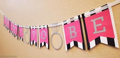 a pink and black banner with scissors hanging from it's sides that says boo