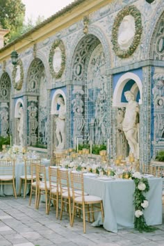 an outdoor dining area with tables and chairs set up in front of a blue wall