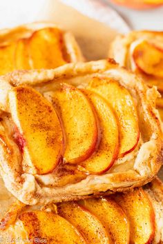 three pieces of pie with sliced peaches on top sitting on a piece of parchment paper