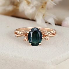 a ring with an oval green stone surrounded by vines and leaves on top of it