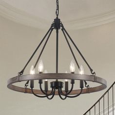 a chandelier with five lights hanging from the ceiling in a room next to stairs