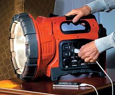 a person is plugging in to an orange and black speaker on a table with other items