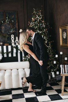 a man and woman kissing in front of a christmas tree