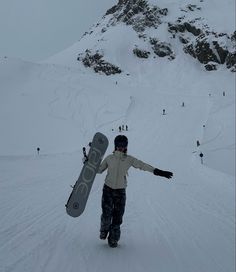 a snowboarder holding his board in the middle of a snowy mountain side area