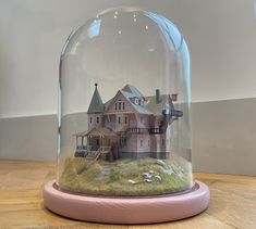 a house under a glass dome on top of a wooden table