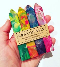 a person holding a box of crayon sixs in their left hand, with a tag on it