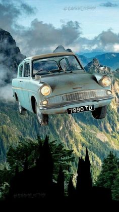 an old car is flying through the air above trees and mountains with clouds in the background