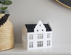 a white house sitting on top of a table next to a vase with a plant