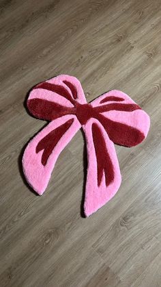 a pink and red rug on the floor next to a white cat toy with a bow