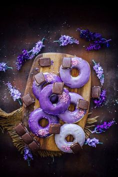 doughnuts with purple icing and sprinkles on a cutting board