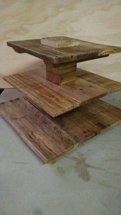 a table made out of wooden planks on top of a cement floor next to a black cat