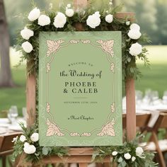 a sign that is sitting on top of a wooden easer with flowers around it