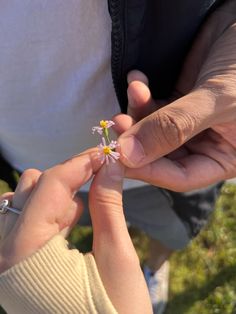 two people are holding small flowers in their hands