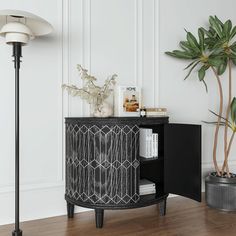 a black and white cabinet next to a potted plant in a room with wood flooring