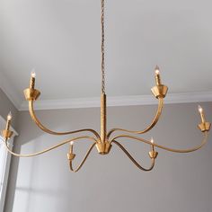 a gold chandelier hanging from the ceiling in a room with gray walls and white trim