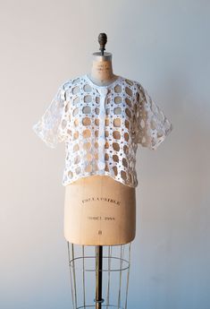 "Fun 1990s white crochet sweater by Michael Simon. Self fabric buttons at the front. Short sleeves. - Fits Up to size large - Bust: 44\" Waist: 45\" Length: 19\" Sleeve Length: 13\" Condition: Excellent! - Small mend at collar" Fitted White Knit Blouse, White Knit Button-up Top, Fitted White Pointelle Knit Blouse, White Pointelle Knit Top For Daywear, Spring Fitted Crochet Top With Buttons, Fitted Crochet Top With Buttons For Spring, White Fitted Crochet Top With Knit Fabrication, White Open Knit Blouse For Spring, White Crochet Lace Cardigan For Summer