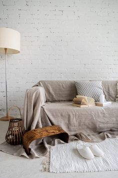 a living room with a couch, lamp and pillows on the floor in front of a white brick wall