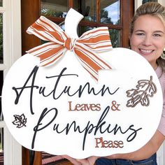 a woman holding up a sign that says autumn leaves and pumpkins please