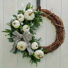 a wreath with white pumpkins and greenery