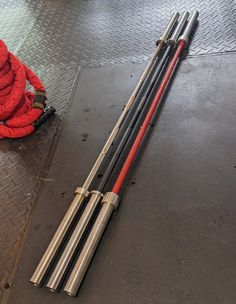 three metal poles laying on the ground next to a red jacket and umbrella bag,