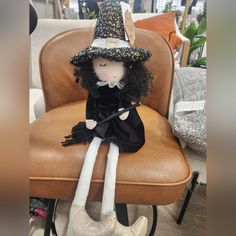 a doll sitting on top of a chair wearing a witches hat and black dress with white legs