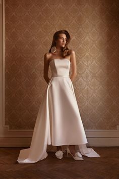 a woman in a white dress standing on a wooden floor