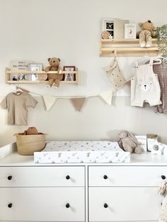 a baby's room with white dressers and teddy bears hanging on the wall