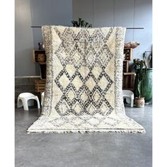 a large white and black rug on top of a floor next to a plant in a room